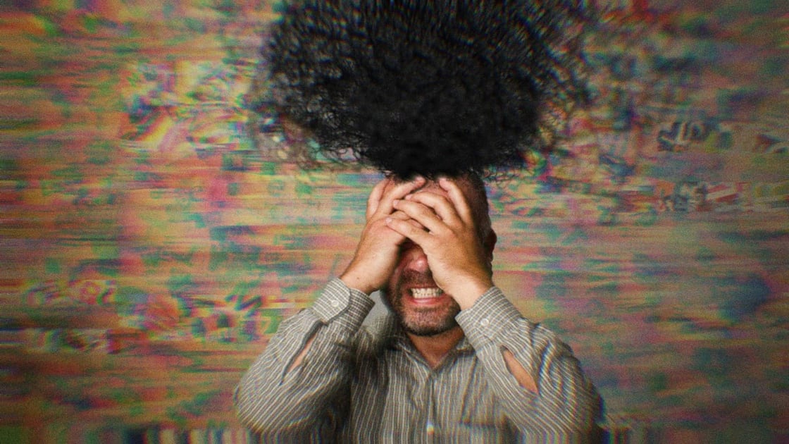 A man with his hands on his head in frustration. An abstract black cloud rises from his brain, symbolizing chaos