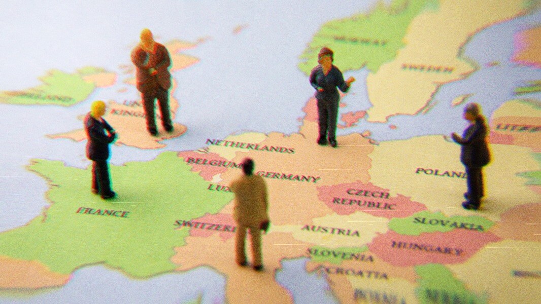 Figurines of people standing on a partial map of Europe.