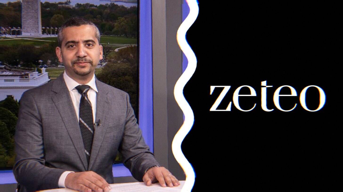 An image of Mehdi Hasan sitting at a desk alongside the logo for his media platform, Zeteo